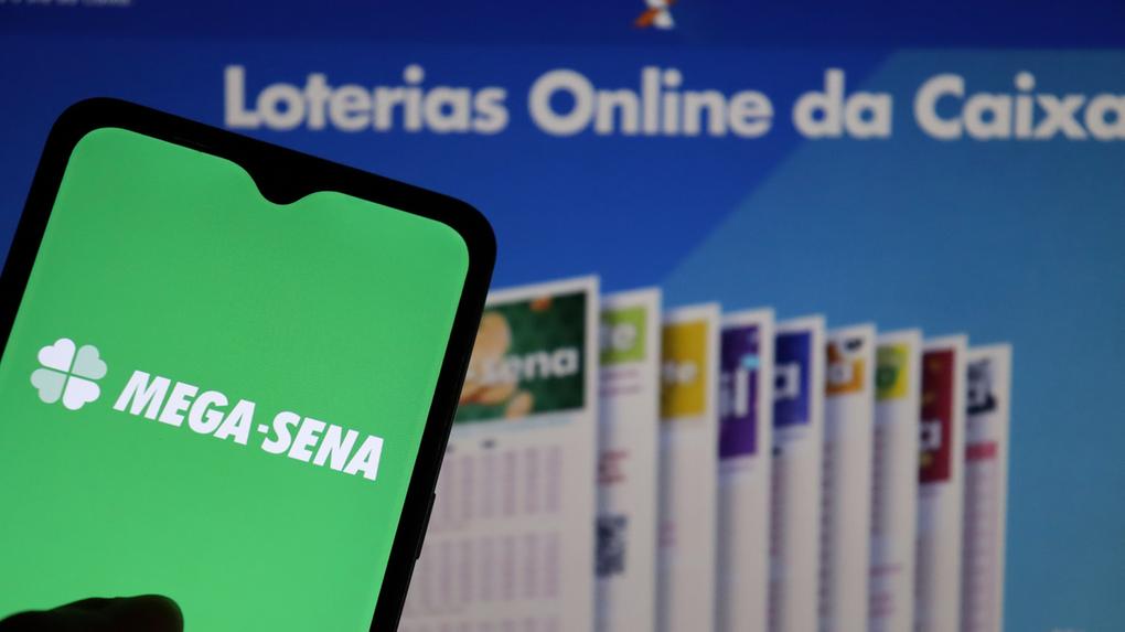 Logotipo da loteria Mega Sena na tela de um smartphone, site da Loterias Caixa ao fundo