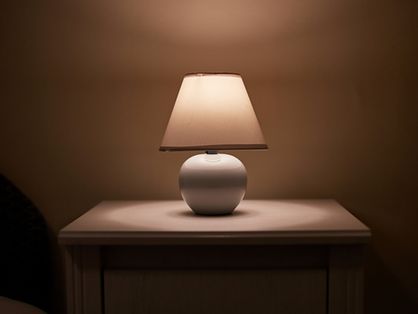 Uma pequena lâmpada brilhando na mesa de cabeceira do quarto, sala escura