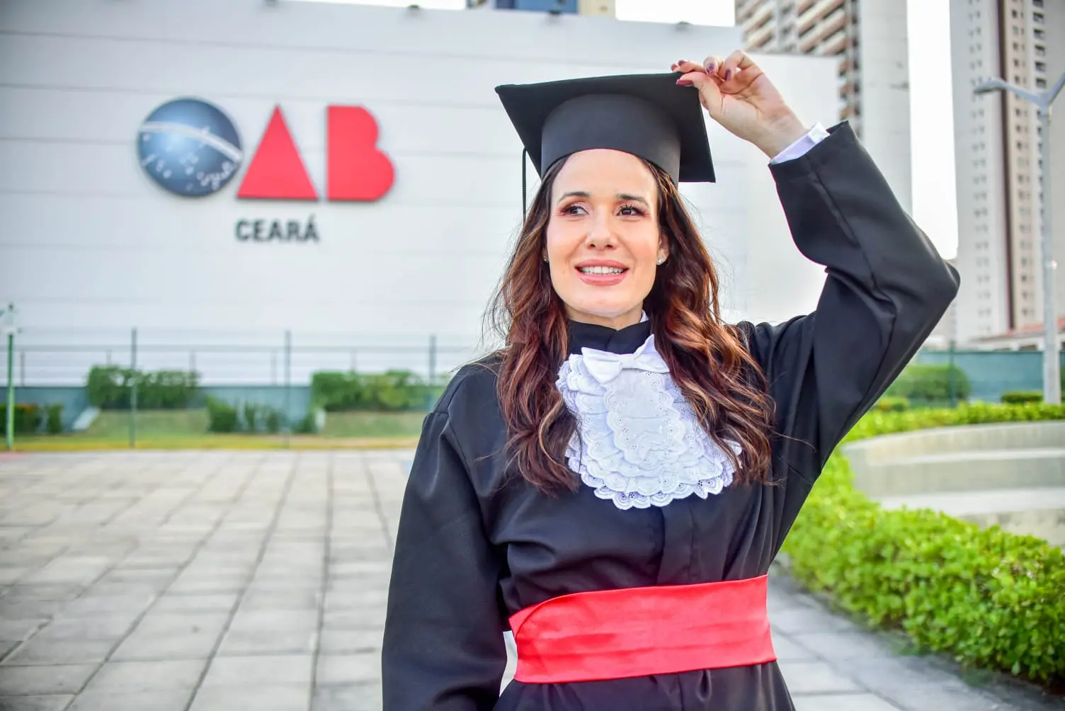 Aluna Daniela Uchoa posando de beca em frente à sede da OAB Ceará