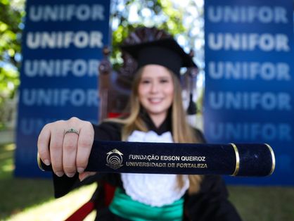 Graduanda com beca mostrando canudo com diploma
