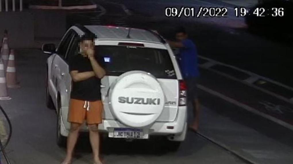 Homem parado ao lado de carro Suzuki Vitara branco em posto de gasolina