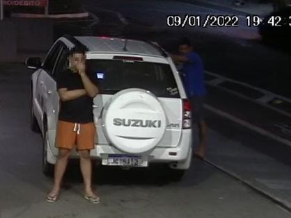 Homem parado ao lado de carro Suzuki Vitara branco em posto de gasolina