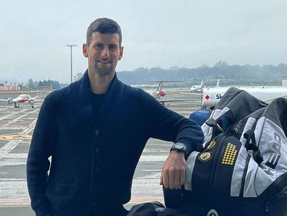Tenista Novak Djokovic está em aeroporto da Austrália, ao lado da bagagem.