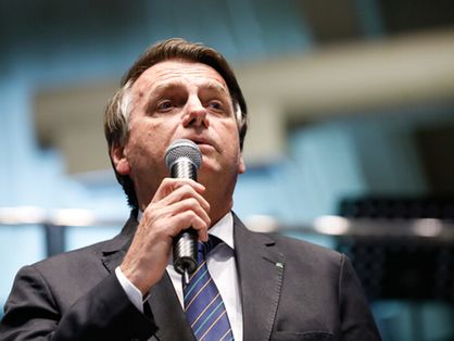 O presidente do Brasil Jair Bolsonaro segurando um microfone.