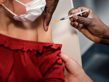 Criança de roupa vermelha sendo vacinada no braço