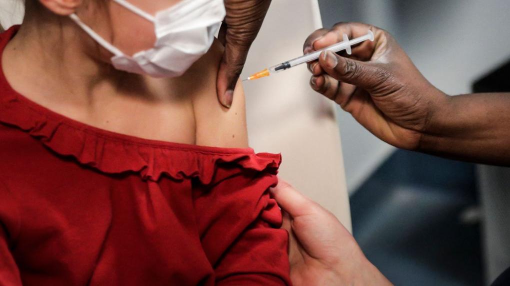 Criança de roupa vermelha sendo vacinada no braço