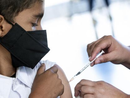 Criança levanta manga da camisa para receber vacina contra a Covid-19.