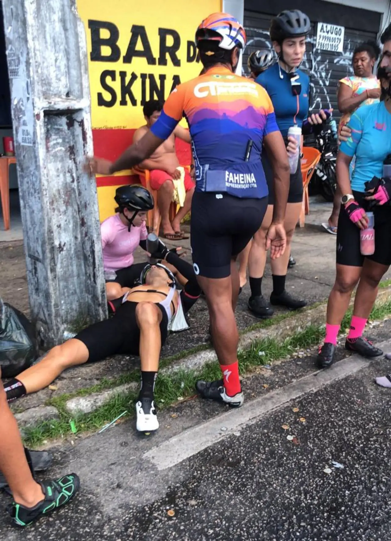 ciclista caído no chão, em frente a um bar