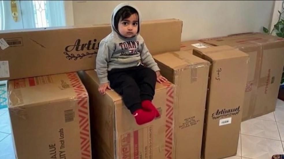 menino sentado agasalhado em cima de várias caixas