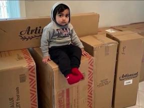 menino sentado agasalhado em cima de várias caixas