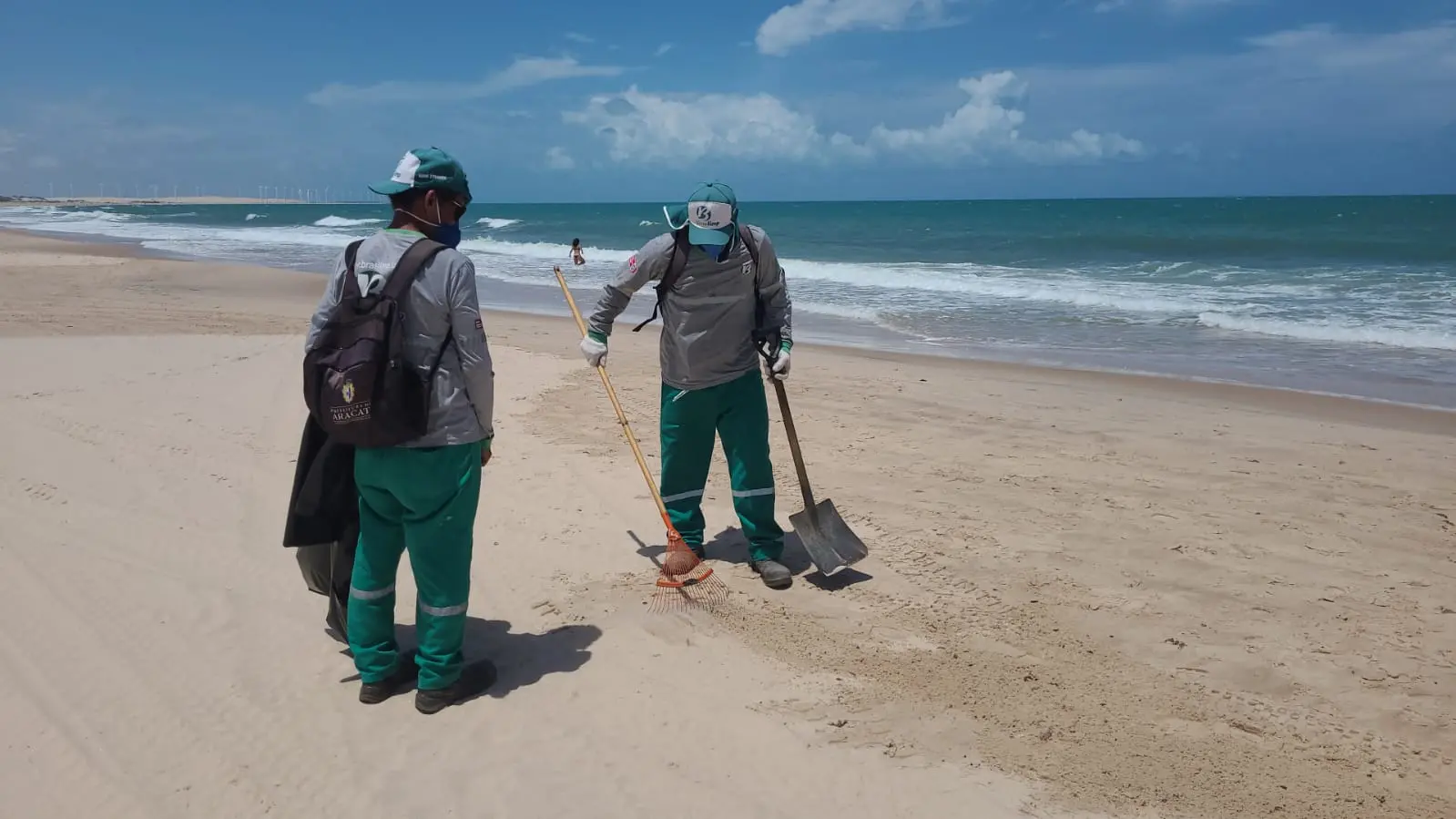 dois homens fardados recolhendo piches com pás