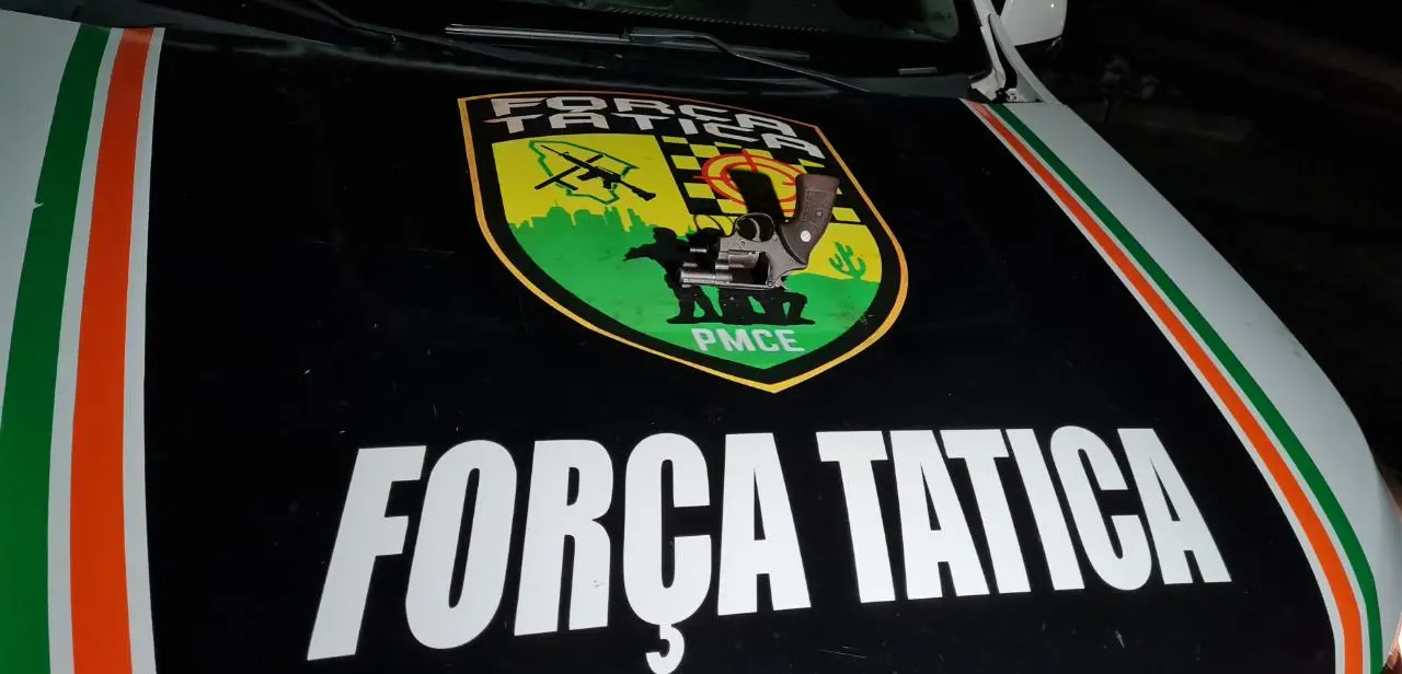 arma sobre capô de viatura com o dizer força tática