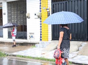 Idosa com guarda-chuva anda em direção a criança com guarda-chuva em Fortaleza