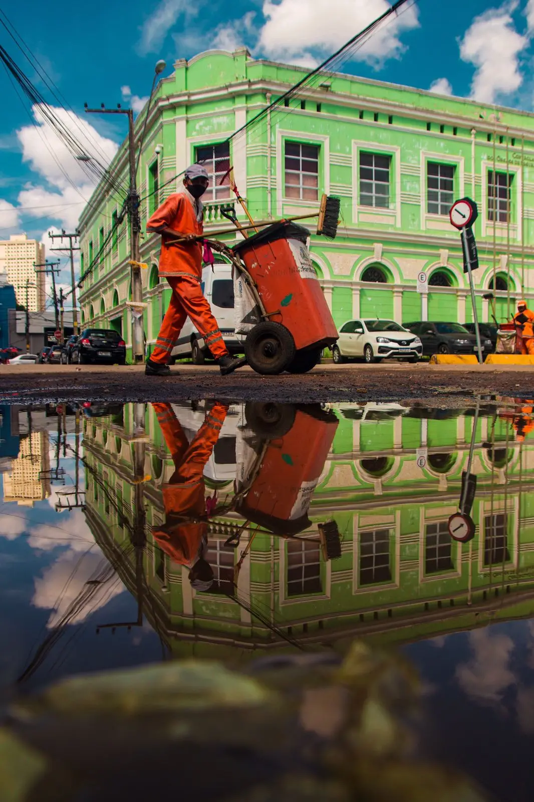 Gari passa em frente a uma poça de água; reflexo é registrado