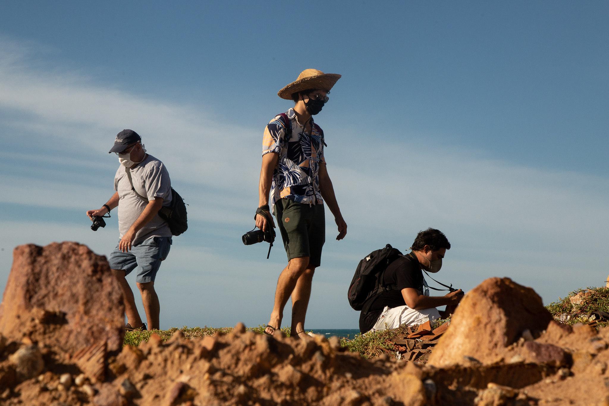 Jovens fotógrafos com suas câmeras sob pedras