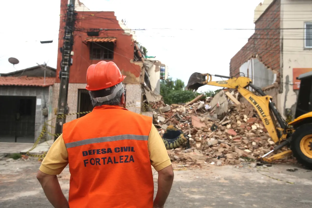 agente da Defesa Civil de costas observando retirada de entulhos da demolição