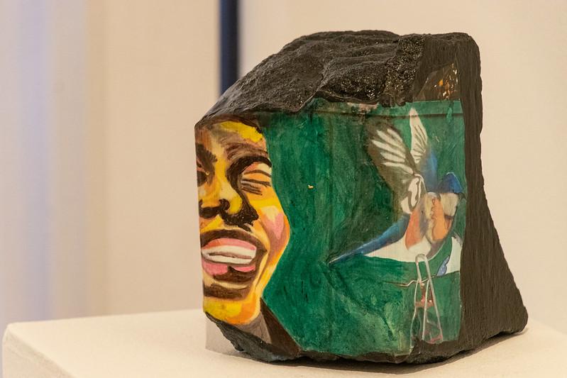 Escultura com desenho de um rosto de uma mulher negra e um pássaro