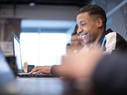 Estudante negro sorri em frente ao computador
