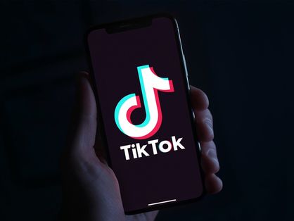 Uma mão segurando um celular aberto no aplicativo TikTok.