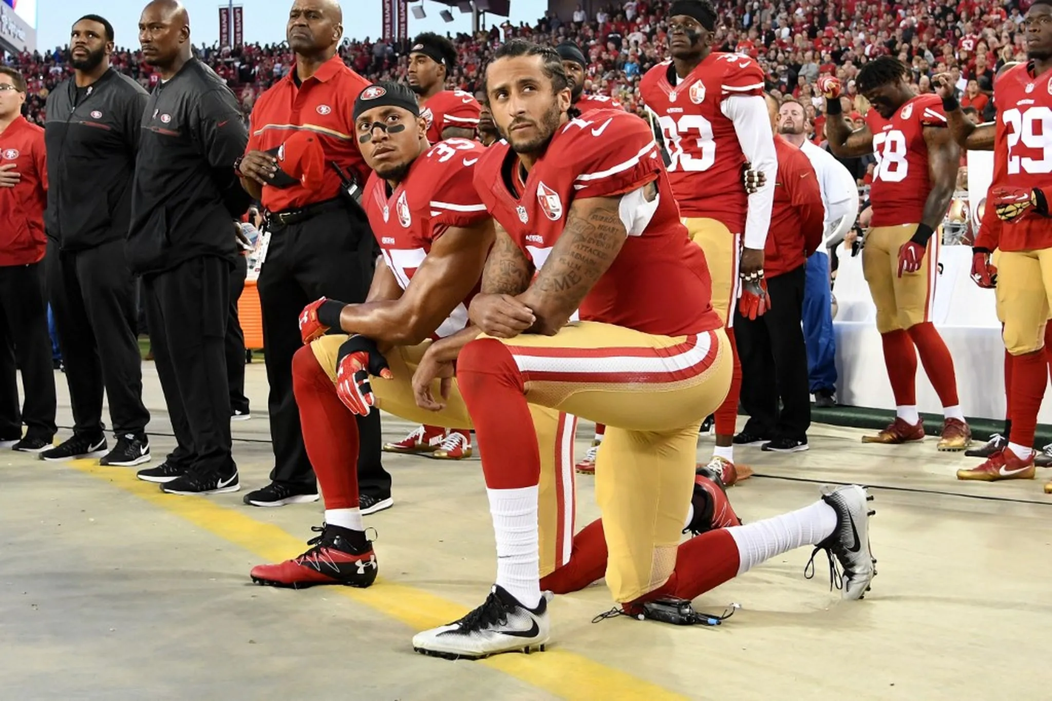 Colin Kaepernick (à direita) e Eric Reid (à esquerda)  se ajoelham em protesto antes da partida contra o Los Angeles Rams