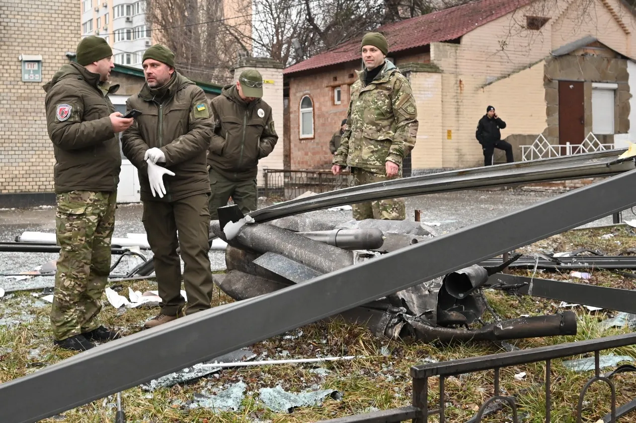 Policiais e seguranças inspecionam restos de um projétil em uma rua em Kiev