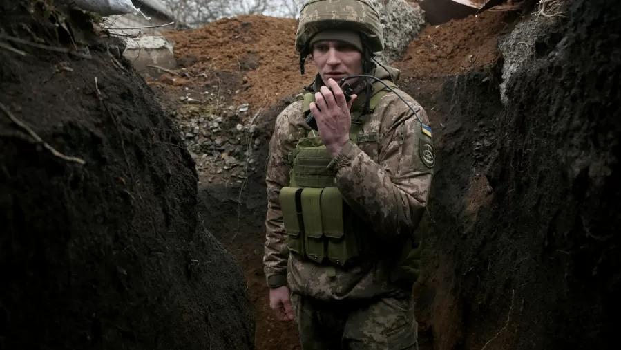 Soldado ucraniano fala em walk-talk. Ele está dentro de uma cratera.