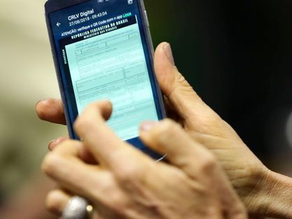 Mãos manuseiam celular com o aplicativo da Carteira Digital de Trânsito aberto