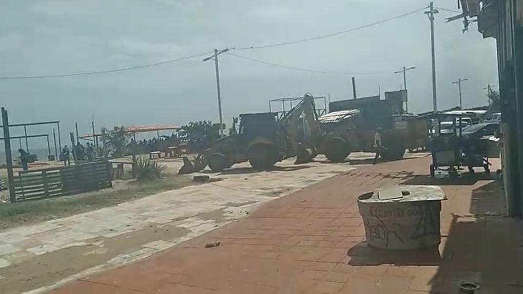 Tratores sobre calçadão na Comunidade do Poço da Draga, na Praia de Iracema, antes de barracas serem destruídas
