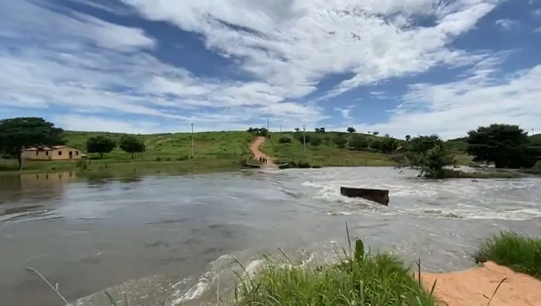 Cheia no Açude Ubaldinho, em Cedro. Ao longo, é possível ver uma casa e uma estrada de terra