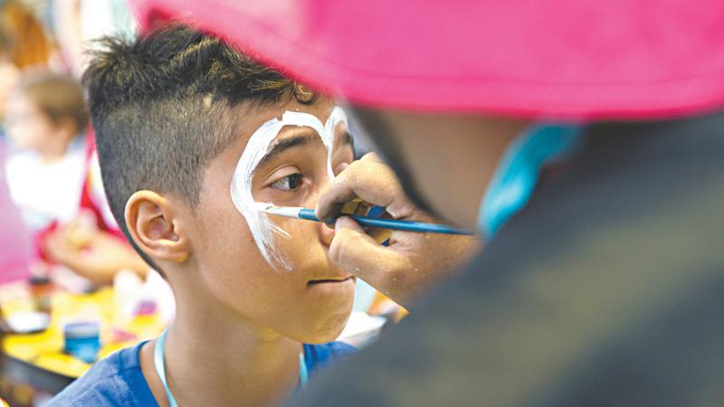 Criança tem o rosto pintado por palhaço em ação no Espaço Mais Infância, na Praça Luíza Távora.