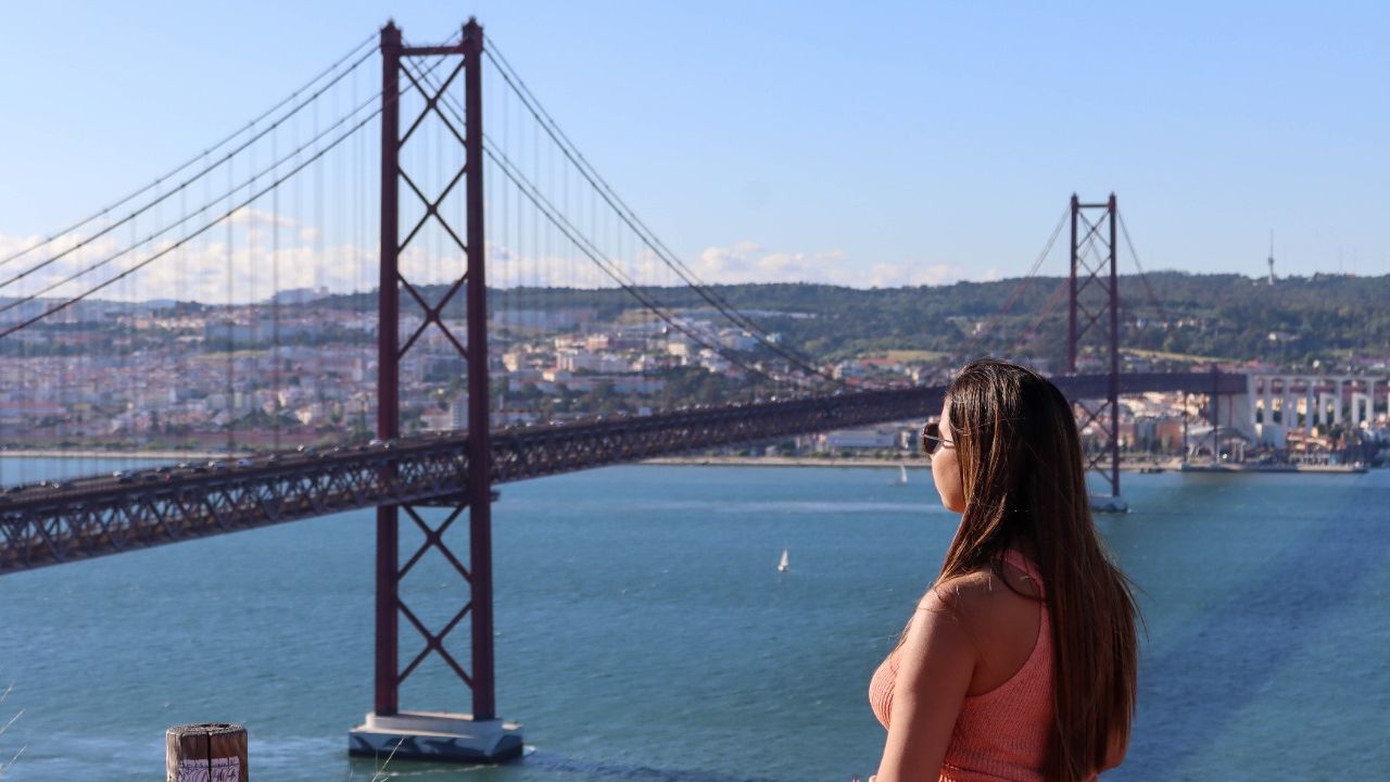 Mulher olha para ponte em Lisboa, Portugal