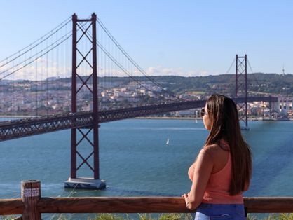 Mulher olha para ponte em Lisboa, Portugal