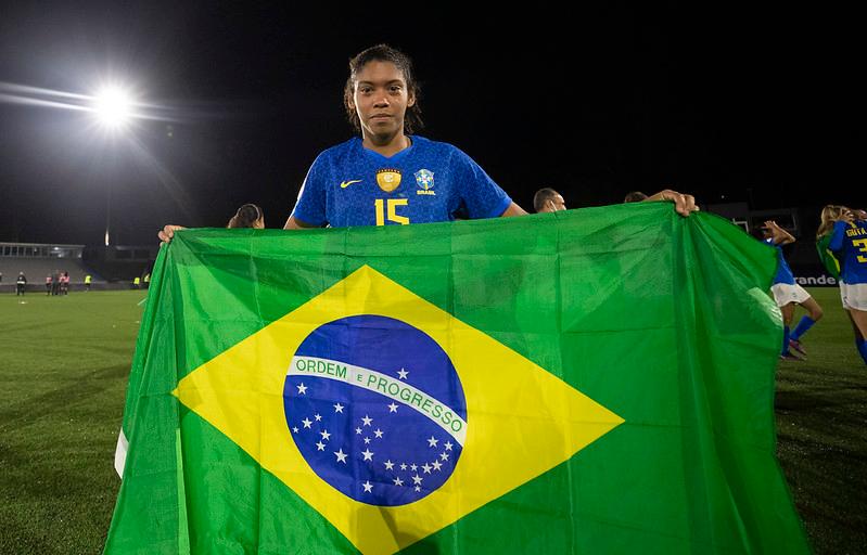 Imagem mostra mulher segurando a bandeira do Brasil