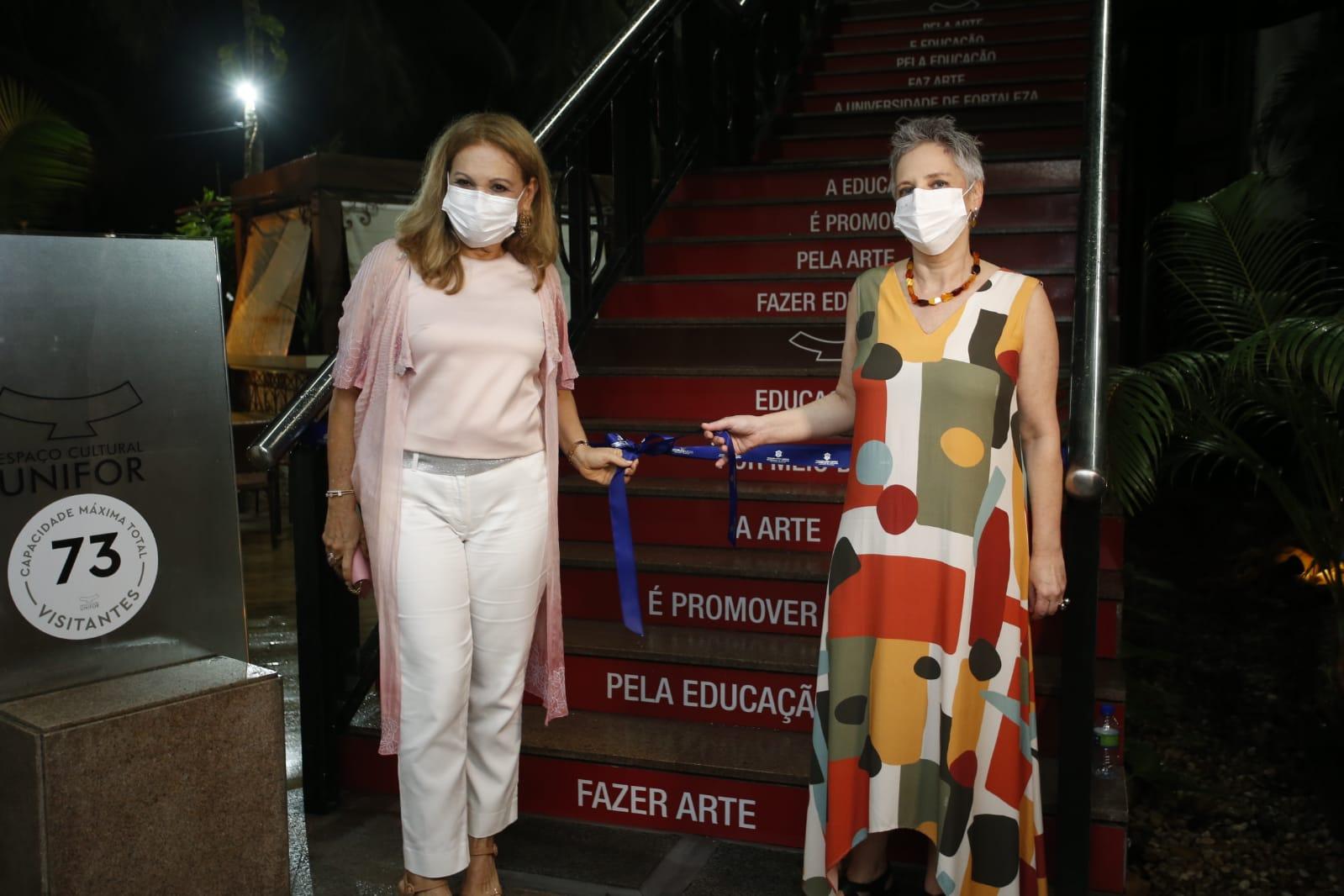 Lenise Queiroz e Regina Teixeira de Barros seguram faixa de abertura da exposição