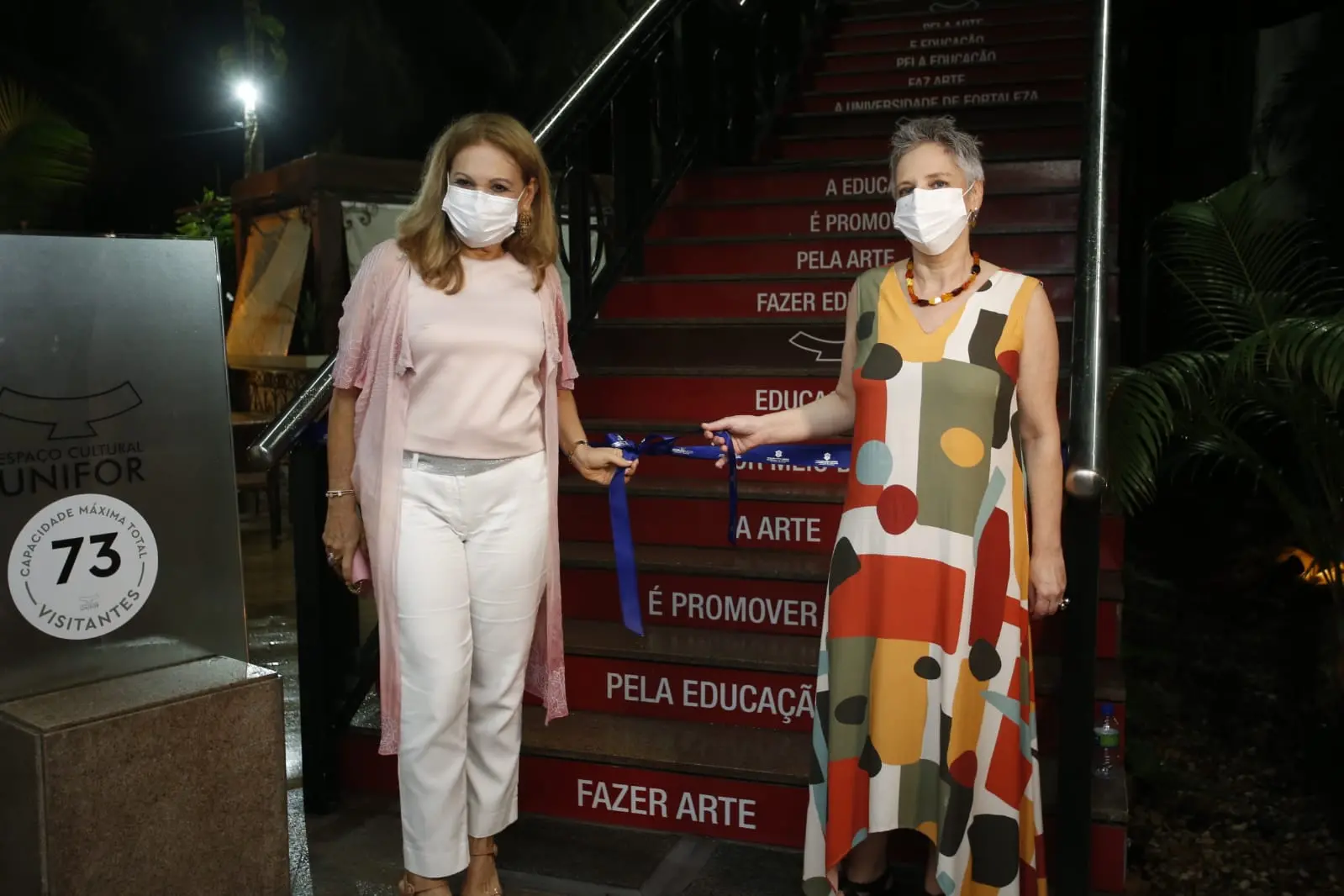 Lenise Queiroz e Regina Teixeira de Barros seguram faixa de abertura da exposição