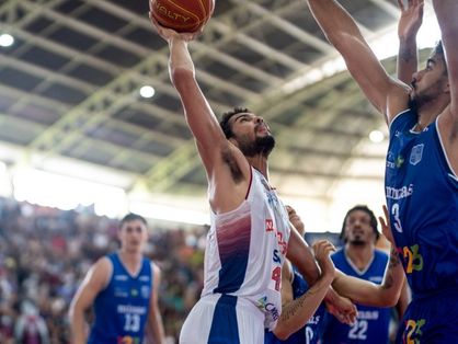 Imagem mostra jogadores disputando bola de basquete no alto