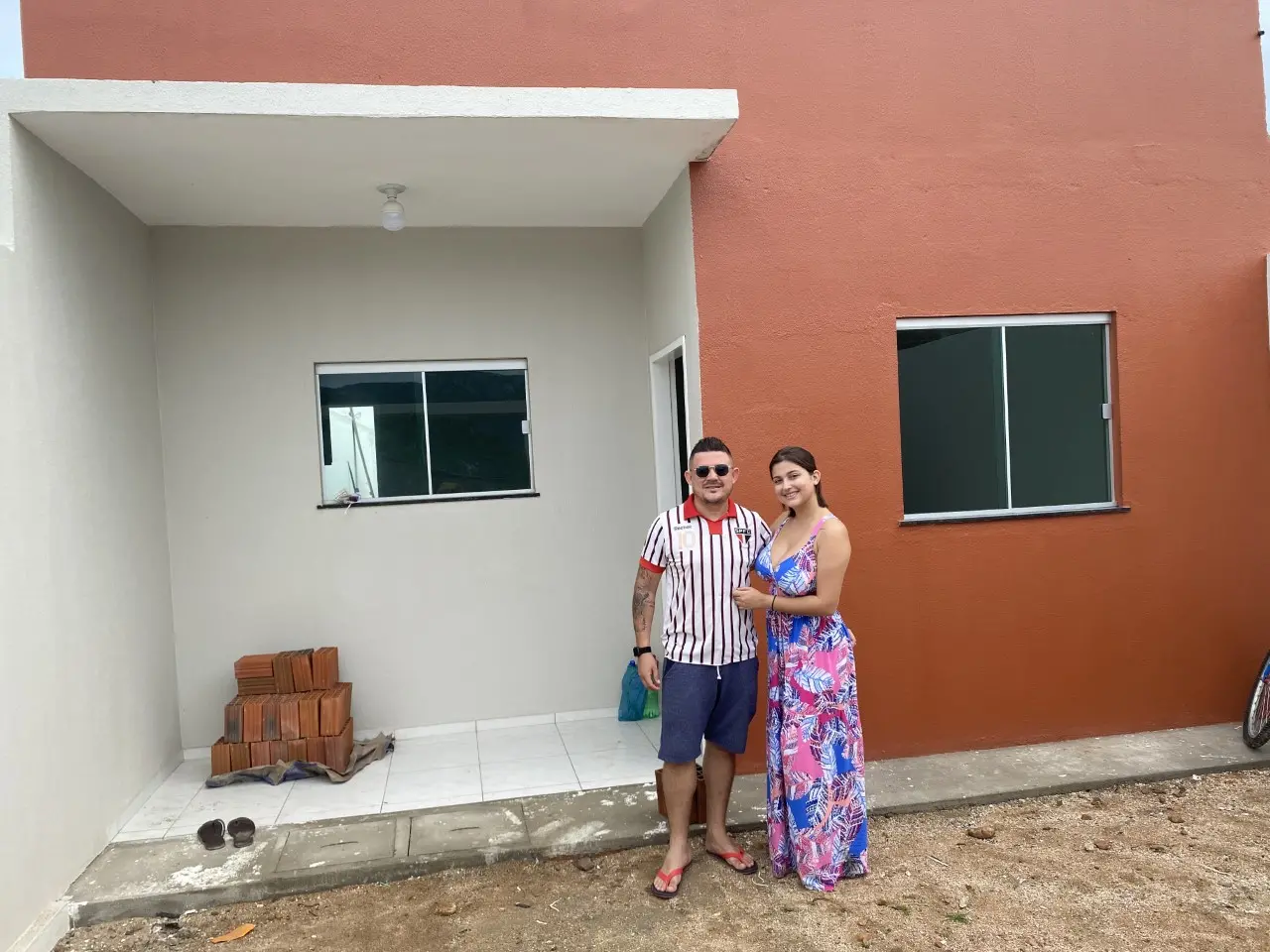 casal abraçado em frente a casa