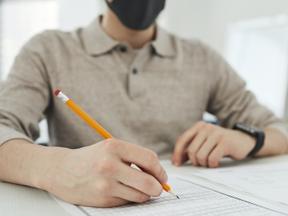 Homem escrevendo com lápis em papel