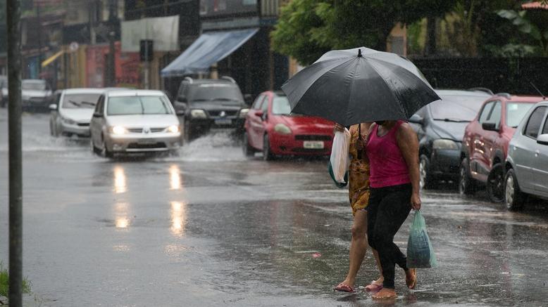 Mulheres atravessam rua sub forte chuva em Fortaleza