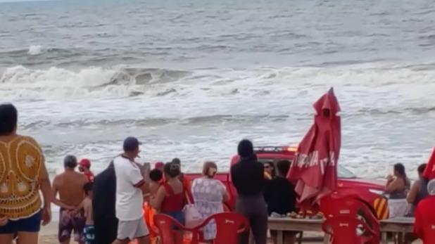 Pessoas se aglomeram na praia da Sabiaguaba para ver resgate de vítima de afogamento.