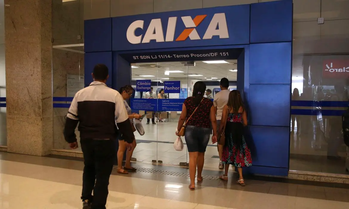 Pedestres entram em uma agência da Caixa Econômica Federal