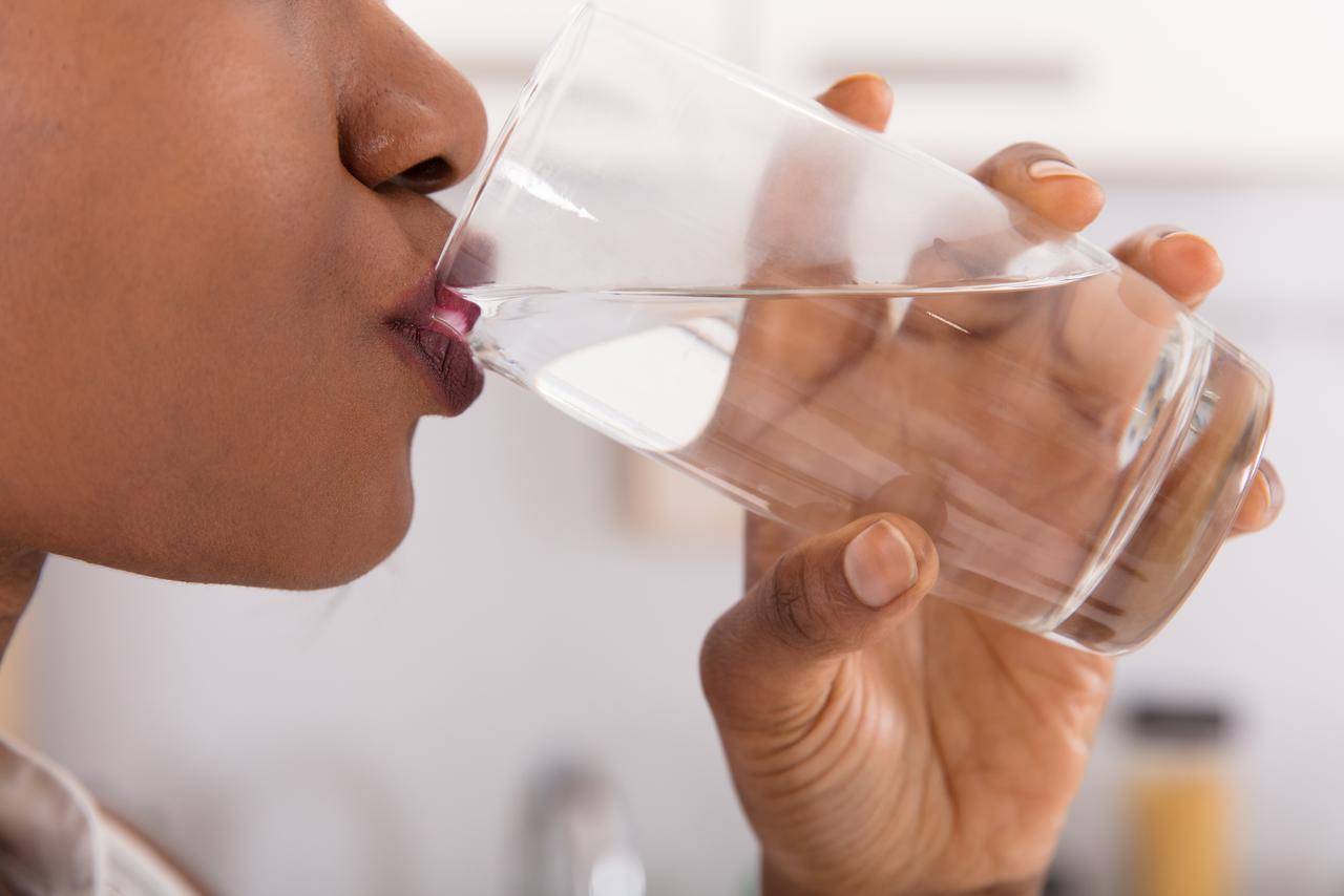 Mulher negra bebendo um copo com água