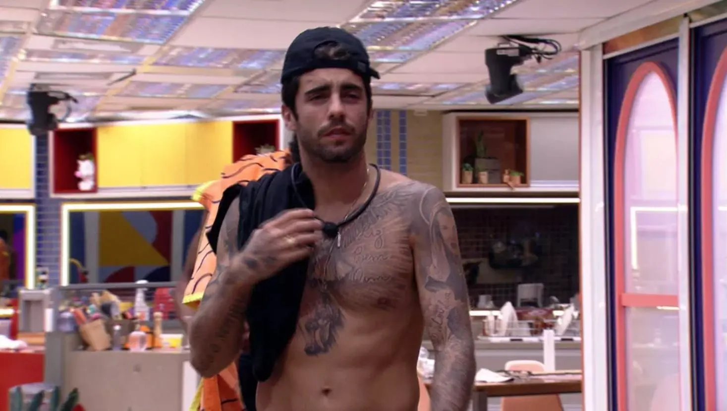 Pedro Scooby segurando camisa preta sobre o ombro