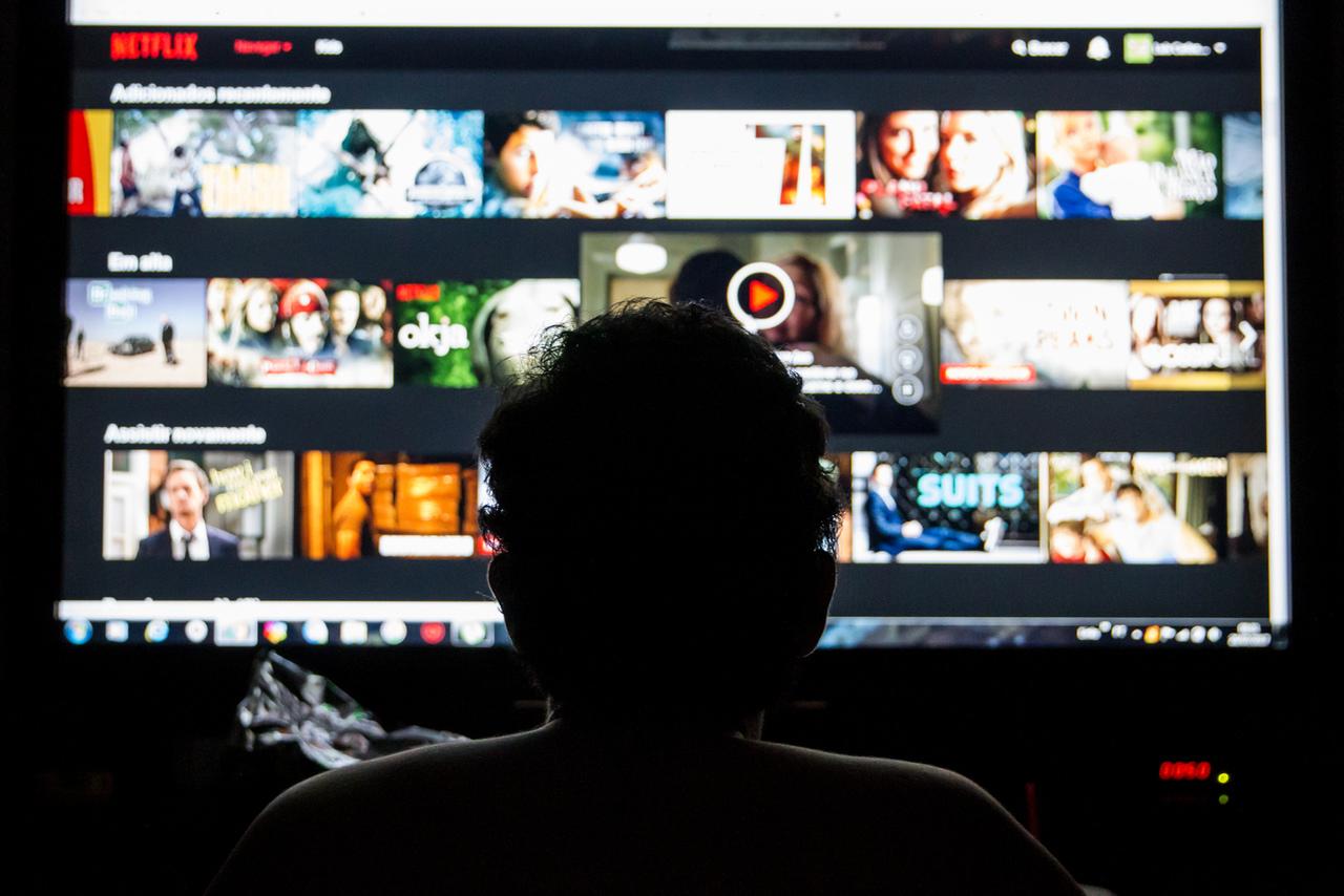 Silhueta de menino em frente à televisão