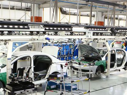 Imagem mostra veículos sendo montados no interior de uma fábrica de carros