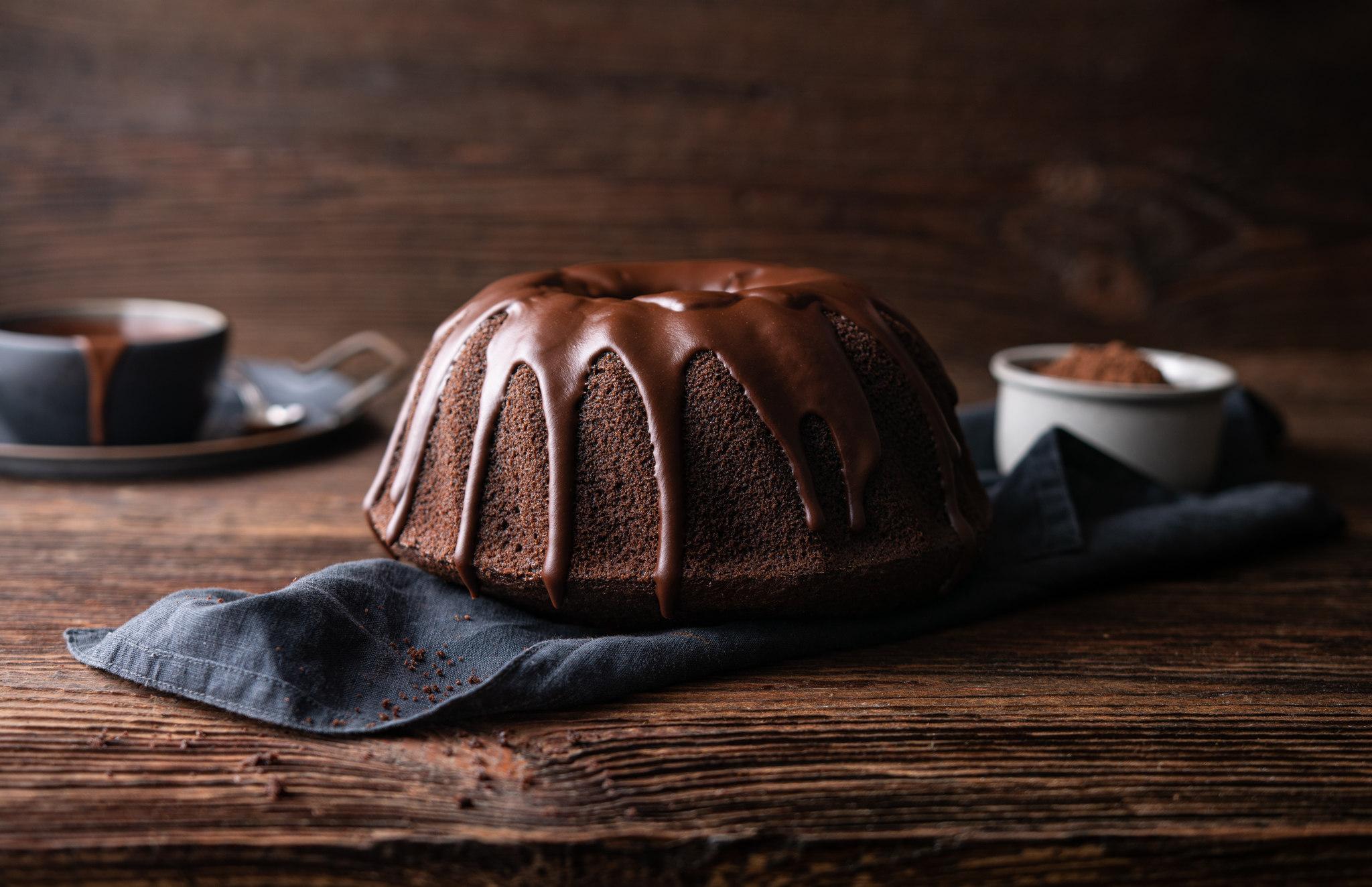 Bolo de chocolate sobre um pano azul escuro disposto em um fundo escuro