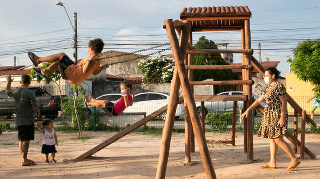 Crianças brincam em balanço na praça