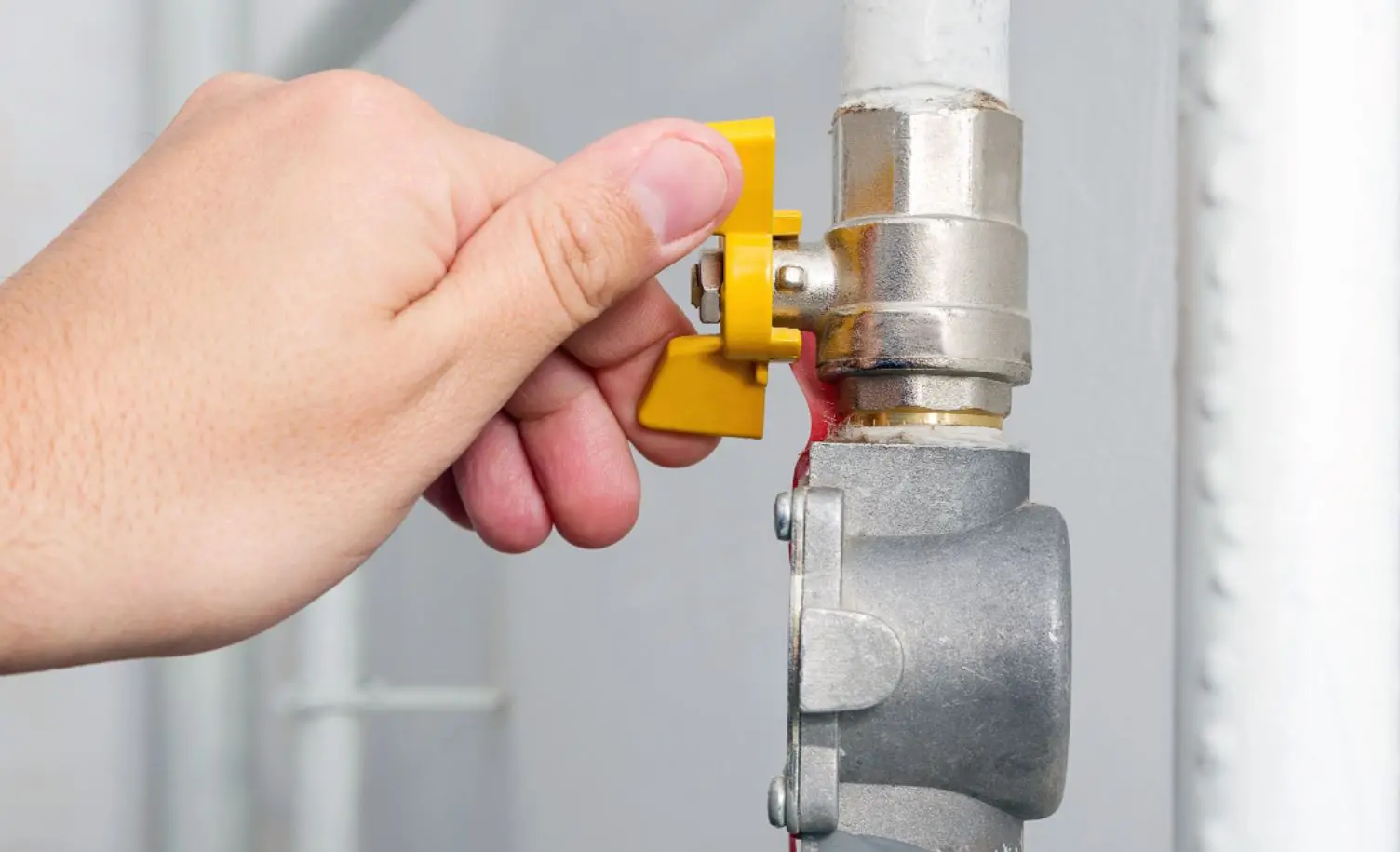 Mão fechando válvula de encanamento de gás natural