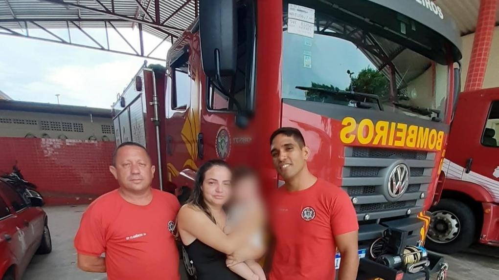 Dois bombeiros e uma mãe segurando seu filho que havia se engasgado.