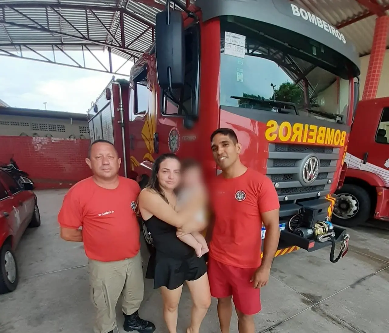 Dois bombeiros e uma mãe segurando seu filho que havia se engasgado.
